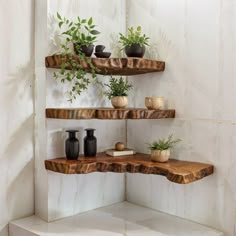 three wooden shelves with plants and vases on them in the corner of a room