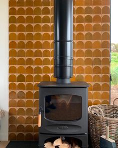 a wood stove sitting next to a pile of firewood in a room with orange tiles on the wall