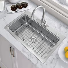 a stainless steel kitchen sink with grids on the front and side, next to some lemons