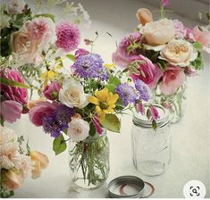 three mason jars filled with flowers sitting on top of a white table next to a pair of scissors