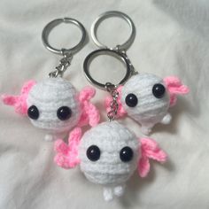 two crocheted keychains with black eyes and pink ears are on a white sheet