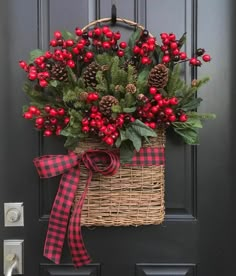 a basket filled with red berries and pine cones hanging on the front door's black door