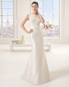 a woman in a white wedding dress standing next to a table with flowers on it