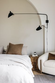 a bedroom with a bed, two chairs and a lamp on the wall next to it