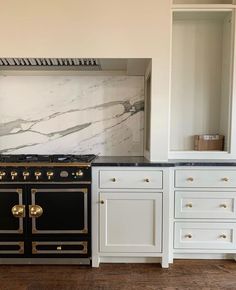 a kitchen with marble counter tops and white cabinets, an oven in the middle is next to a built - in shelving unit