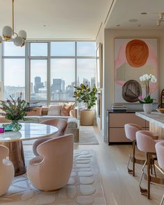 a living room filled with lots of furniture and tall windows next to a dining table