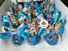 some cupcakes with blue frosting and cartoon characters on them in a box