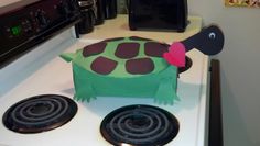 a cake shaped like a turtle sitting on top of a stovetop next to an oven