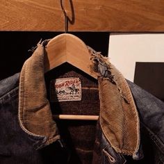 an old pair of jeans hanging on a wooden hanger