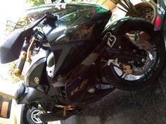 a black motorcycle parked in a garage next to a planter with potted plants