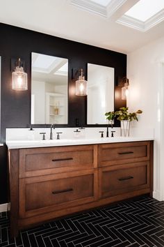 a bathroom with double sinks and two mirrors on the wall next to black tile flooring