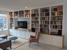 a living room filled with furniture and bookshelves next to a flat screen tv