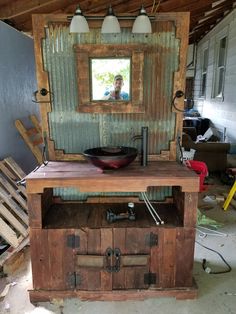 a bathroom vanity made out of an old door with a bowl on it and lights hanging from the ceiling