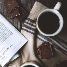 a cup of coffee and some chocolates on a towel with a book next to it