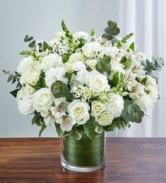 a vase filled with white flowers on top of a wooden table