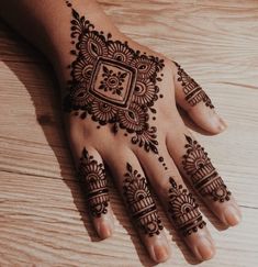 a henna tattoo on someone's hand that is sitting on a wooden table