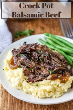 a white plate topped with mashed potatoes covered in meat and gravy next to green beans