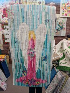 a woman holding up a quilt made from strips of fabric