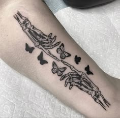 a woman's arm with butterflies on it and a skeleton in the middle of her arm