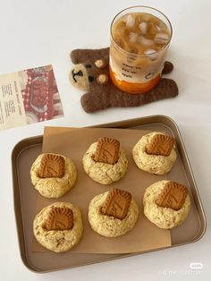 some cookies are sitting on a tray next to a cup of tea and a teddy bear