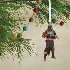 a star wars ornament hanging from a pine tree with ornaments on it's branches