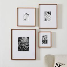 three framed photographs hang on the wall above a chair in front of a white couch