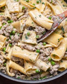 a skillet filled with pasta, peas and ground beef in a creamy cream sauce