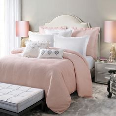 a bedroom with pink bedding and white pillows