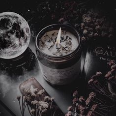 a candle sitting on top of a table next to some dried flowers and a book