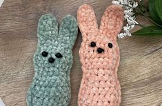 two crocheted bunnies sitting next to each other on top of a wooden table