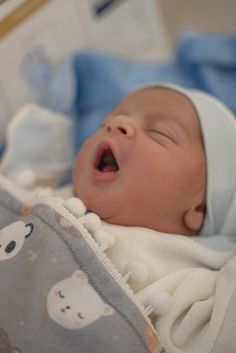 a baby is laying down and yawning with its mouth wide open in the crib