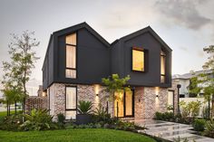 a modern house with two story windows and grass in the front yard at sunset or dawn