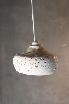 a white light hanging from a ceiling in a room with concrete walls and flooring