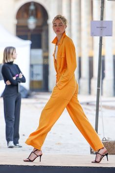 a woman in an orange jumpsuit is walking down the street