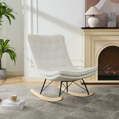 a white rocking chair sitting in front of a fire place next to a potted plant