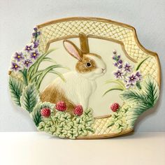 a decorative plate with a rabbit in the center and flowers around it on a shelf