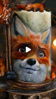 a close up of a cup with a fox on it's face and leaves in the background