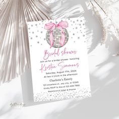 a white and pink bridal shower party card on a table with palm fronds