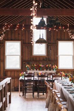 a long table is set up in the middle of a room with lights hanging from the ceiling