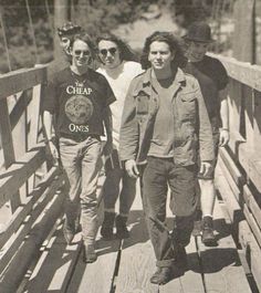 black and white photograph of four people walking across a bridge