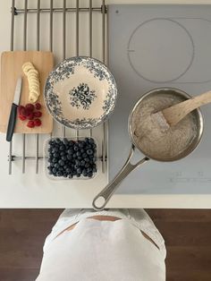 a person standing in front of a stove top with food on the burners and cooking utensils