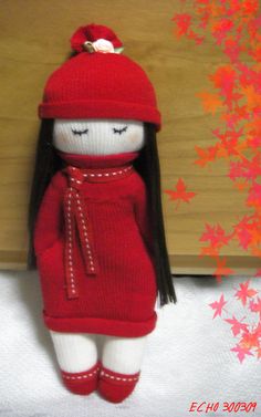 a stuffed doll wearing a red dress and hat