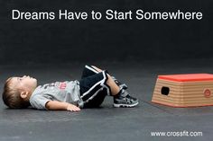 a young boy laying on the ground next to a red box with words that read greatness starts now