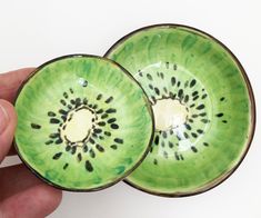 a hand holding a green bowl with black spots on it and another one in the background