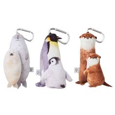 three stuffed animals hanging from hooks on a white background, one penguin and the other penguin