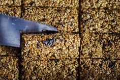 a close up of a knife cutting into some granola bars with blueberries on top