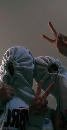 two people with their hands up in the air and one person wearing a hoodie