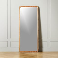 a wooden mirror sitting on top of a hard wood floor next to a white wall