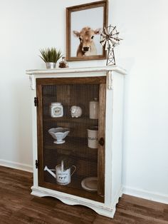 a white cabinet with glass doors and shelves on the top is decorated with items from china