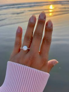 a woman's hand with a diamond ring on it, and the sun setting in the background